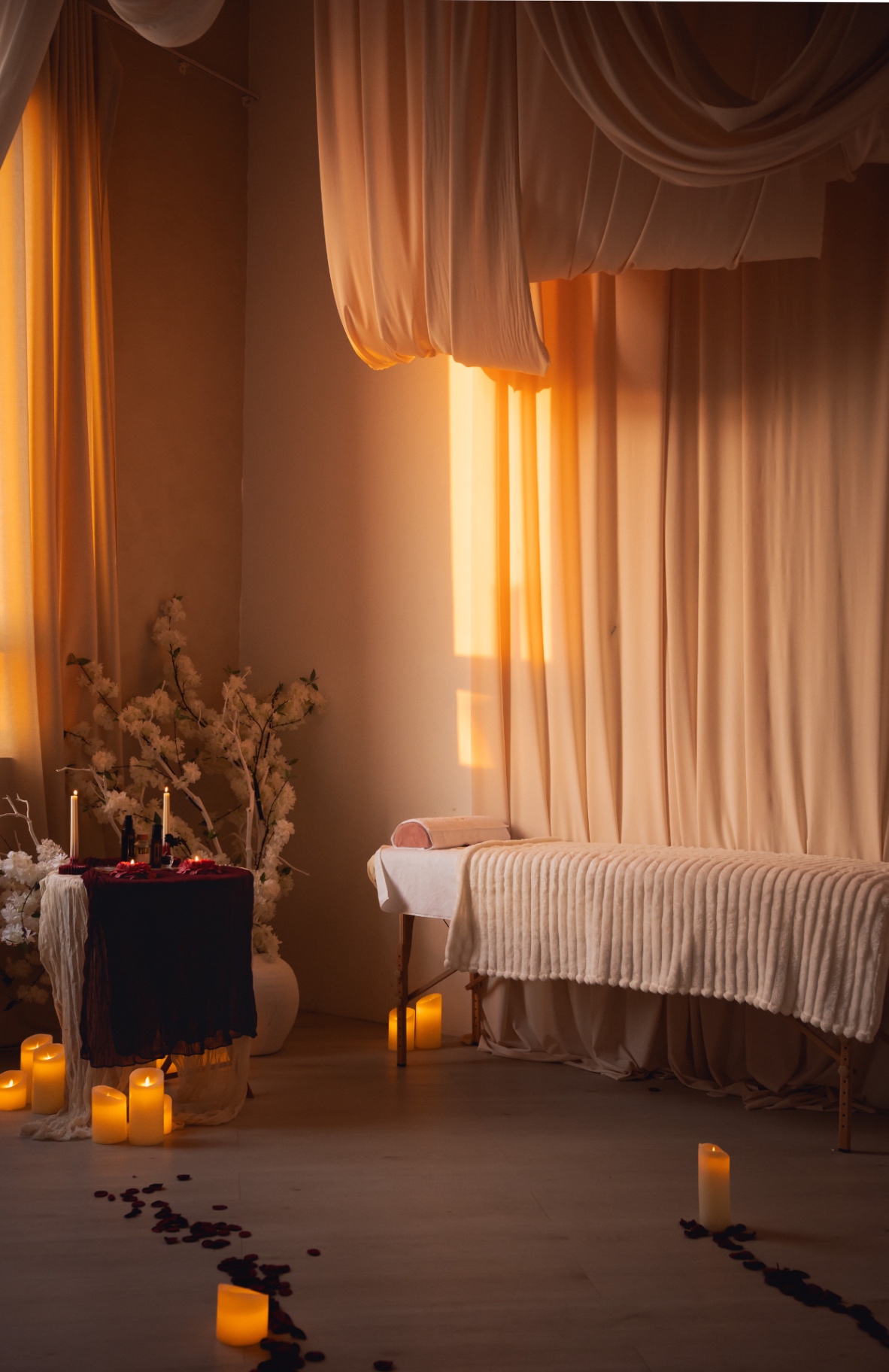 A candlelit ritual room prepared in warm evening light, with flowers, a draped table, and a path of candles